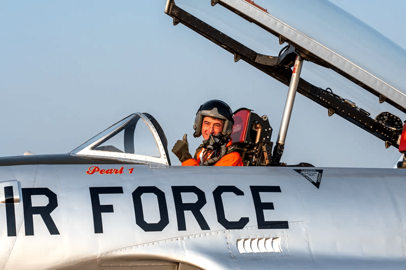 Pilot in single seat airplane giving thumbs up to the camera. 